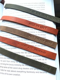 four leather bookmarks with words on them sitting on top of an open book page