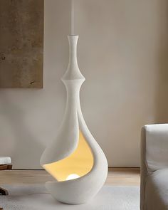 a large white vase sitting on top of a wooden floor next to a chair and table