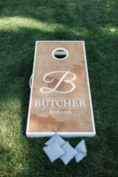 a cornhole board with two napkins on the ground next to it and a bottle opener