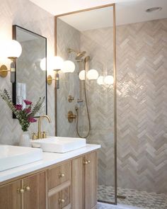 a bathroom with two sinks, a shower and a large mirror on the wall above it