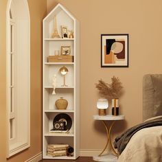 a room with a bed, table and shelf in it that has books on it