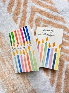 two birthday cards with candles on them sitting next to each other, one has a happy birthday written on it