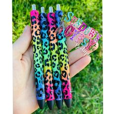 three pens in the palm of someone's hand, one with an animal print on it