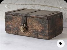 an old wooden box sitting on top of a cement floor next to a brick wall