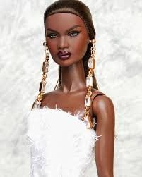 a barbie doll wearing a white dress with feathers on it's head and earrings