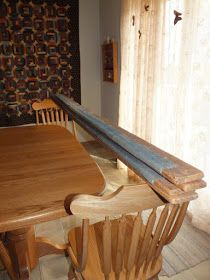 a wooden table with two chairs and a bench in front of a curtained window