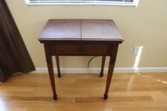 a small wooden table sitting on top of a hard wood floor next to a window