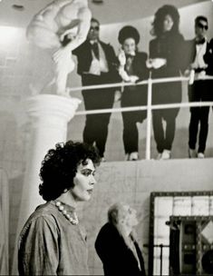 black and white photograph of woman standing in front of wall with people on it's sides