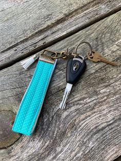 two keys that are sitting on top of a piece of blue material and one has a keychain attached to it