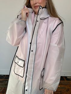 Crafted from a translucent material, this raincoat provides waterproof protection without compromising on style. Its long length offers ample coverage, keeping you dry from head to toe, while the translucent design adds a modern touch, allowing your outfit to peek through. The black trim along the edges of the raincoat adds a chic and sophisticated contrast, elevating its overall aesthetic. The sleek black details not only enhance the coat's visual appeal but also provide structural reinforcemen Rainy Coat, Trendy Winter Raincoat For Rainy Weather, White Hooded Raincoat For Rainy Season, Oversized Nylon Raincoat For Rainy Weather, Trendy Spring Raincoat For Rainy Weather, Oversized Waterproof Long Sleeve Raincoat, Oversized Long Sleeve Waterproof Raincoat, White Raincoat For Rainy Fall Weather, White Raincoat For Fall Rainy Weather