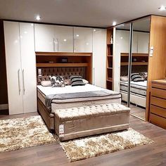 a bedroom with a bed, dressers and mirror in it's center area