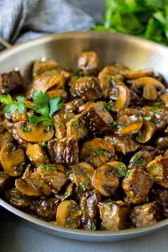 a metal bowl filled with mushrooms and parsley