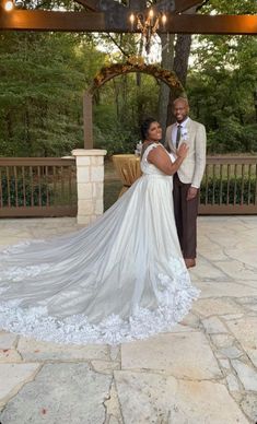 a bride and groom pose for a photo under the gazebo