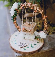 a small basket is sitting on top of a tree stump with flowers and leaves around it