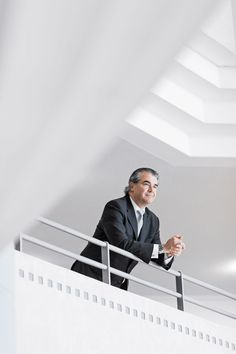 a man in a suit and tie standing on a balcony railing with his arms crossed