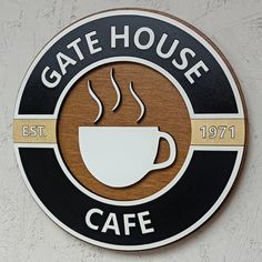 a sign that says gate house cafe on the side of a building with a cup of coffee in it