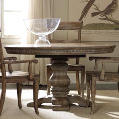 a wooden table with chairs around it and a bowl on top of the dining room table