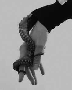 a hand holding an octopus in the air with it's tentacles wrapped around it