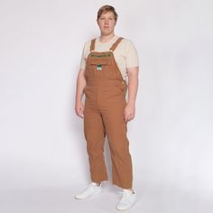 Vintage tan canvas bib overalls by Liberty, with a zipper fly. Measurements and Condition:  Fits like: Labeled 38x30 Fabric: Cotton denim  Brand: Liberty Condition: Very good, with some small bleach spots and a couple other faint discolorations (mainly on the legs). Length: 61" as shot - straps adjust Waist: 42" Hips: 46" - taken at the bottom of the button opening Rise: 12.5" Inseam: 28" Shown on a 6'4" model, who usually wears a size extra large. See our FAQ for more info on sizing and conditi Retro Cotton Overalls For Streetwear, Vintage Brown Cotton Overalls, Retro Cotton Shortalls With Bib Front, Retro Cotton Bib Front Shortalls, Workwear Jumpsuit, Overalls 90s, Mens Overalls, Bib Overalls, Denim Branding