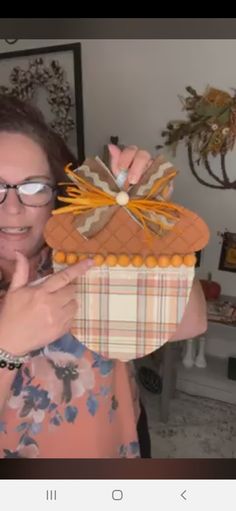 a woman holding up a basket made out of fabric and paper with bows on it