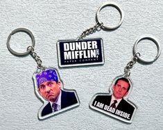 three key chains with two pictures of the same person and one that says dunder mifflin