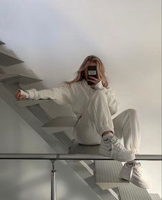 a woman sitting on top of a stair case holding a cell phone up to her face