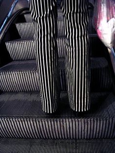 two people standing at the bottom of an escalator with their feet on the handrails