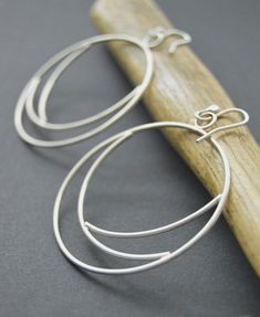 Silver hoops made from sterling silver 16 gauge wire.  These Eclipse earrings were shaped and meticulously pieced together by hand.  The hoops were tumbled for several hours to give them strength and durability, afterwards buffed to a brush finish.  One of my favorite designs!  An everyday statement earring that is unique and crafted with passion.~Length 2.25 inches~Width 2 inches~The earrings pictured are not the exact ones that you will receive, but a twin version will be duplicated with sligh Modern Wire Wrapped Hoop Earrings, Minimalist Handmade Hoop Wrap Earrings, Unique Hand Forged Sterling Silver Hoop Earrings, Modern Handmade Hoop Wrap Earrings, Handmade Silver Small Hoop Wrap Earrings, Handmade Sterling Silver Hoop Wrap Earrings, Modern Sterling Silver Small Hoop Wrap Earrings, Handmade Small Hoop Sterling Silver Wrap Earrings, Modern Handmade Sterling Silver Hoop Earrings