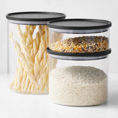 three containers filled with food sitting on top of a white counter next to each other