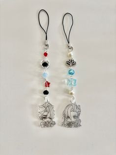 two necklaces with charms attached to them on a white surface, one has a cartoon character