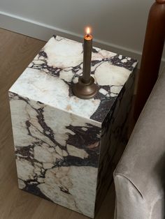 a marble block with a lit candle in it sitting on the floor next to a chair