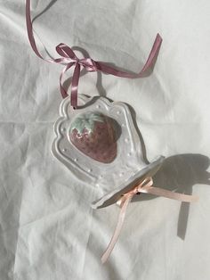 an ornament shaped like a strawberry with a pink ribbon hanging from it's side