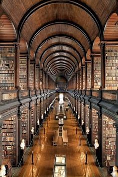 the inside of a large library with many bookshelves and stairs leading up to it