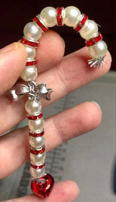 a hand holding a red and white beaded bracelet