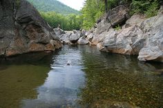 a man swimming in a river surrounded by rocks