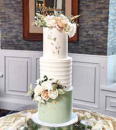 a three tiered wedding cake with flowers on the top and bottom, sitting on a table in front of a mirror