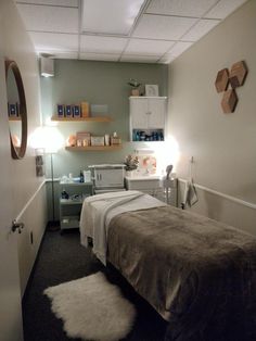 a treatment room with a bed, sink and shelves on the wall in front of it