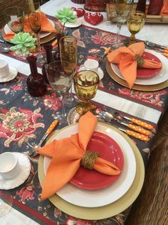 the table is set with orange napkins and place settings