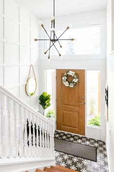 an entryway with stairs and a wreath hanging on the front door, surrounded by white walls