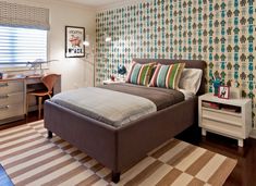 a bed room with a neatly made bed next to a dresser and a desk in front of a window