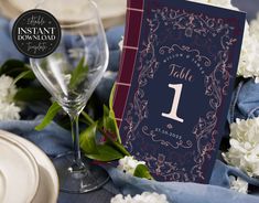 a table setting with place cards, wine glasses and napkins on the tablecloth