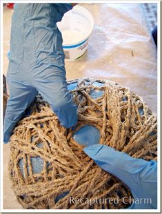 a person in blue gloves and rubber gloves working on a ball of jute rope