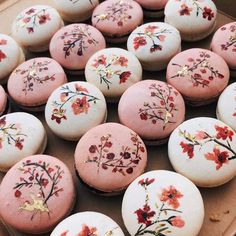 there are many pink and white macaroons with flowers on them in a box