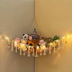 several stuffed animals are sitting on a string with lights strung around them and hanging from the wall