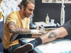 a man getting his tattoo done at the same time as he sits in a chair