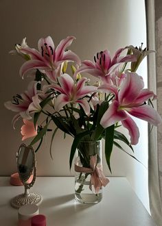 a vase filled with pink flowers sitting on top of a table next to a mirror