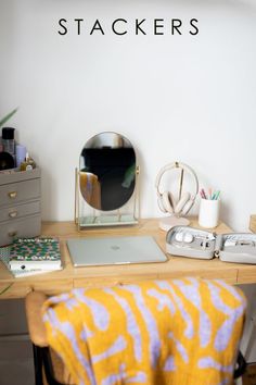 a laptop computer sitting on top of a desk next to a mirror and other items