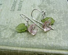 "These are cute little purple Czech glass flowers that we swirled some sterling silver tendrils around and added a peridot green colored Czech glass leaf. All the wire including the ear wires are sterling silver. The entire earring measures about 1\" (2.5cm) from the top of the ear wire to the bottom of the earring. The widest part across measures about 5/8\" (1.5cm). Check out our glass earrings/pendants section of our shop to see this design in other colors and our other glass flower designs a Nickel Free Green Jewelry For Spring, Dainty Green Flower Earrings With Ear Wire, Cute Silver Spring Jewelry, Cute Silver Jewelry For Spring, Whimsical Hypoallergenic Flower Jewelry, Green Dainty Flower Drop Earrings, Delicate Green Jewelry For Spring, Whimsical Silver Flower Jewelry, Green Delicate Flower Jewelry