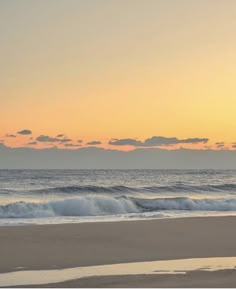 two people walking on the beach at sunset