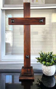 a wooden cross sitting next to a potted plant